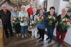 Auf dem Foto stehen neun Frauen und Männer zusammen. Die Frauen halten Blumensträuße in den Händen.