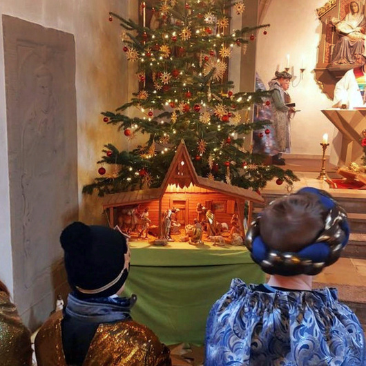 Blick vom Kirchenraum zum Altarraum. Links steht ein geschmückter Christbaum.