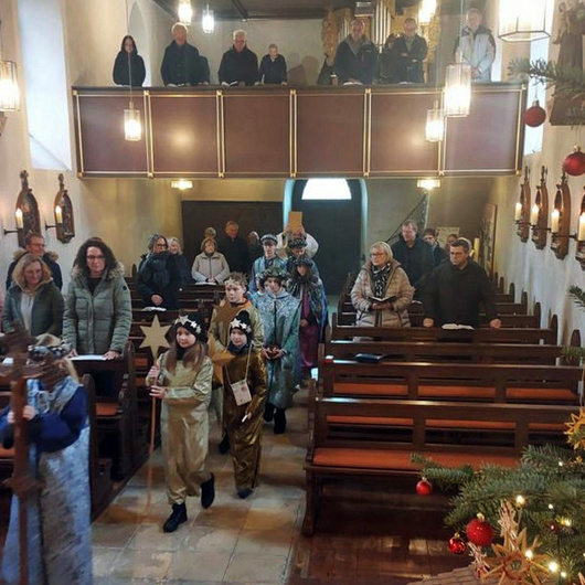Blick vom Altarraum in die Kirche. Im Mittelgang ziehen die Sternsingerinnen und Sternsinger ein.