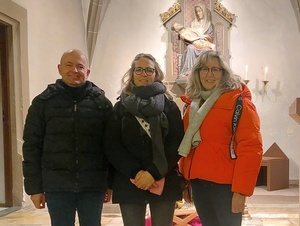 Drei Personen stehen im Altarraum und schauen in die Kamera.